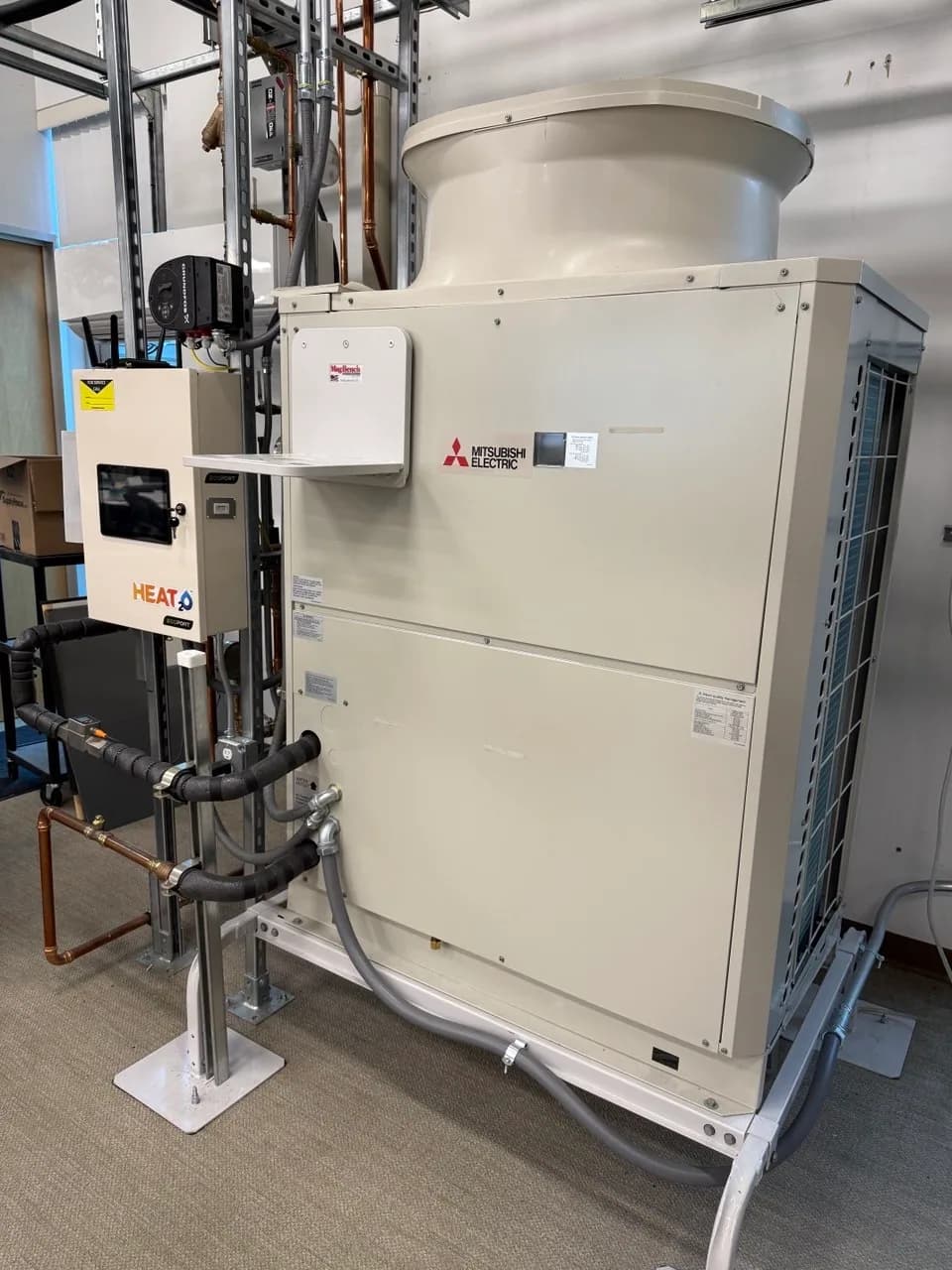 Mitsubishi commercial heat pump outdoor unit mounted against a building wall