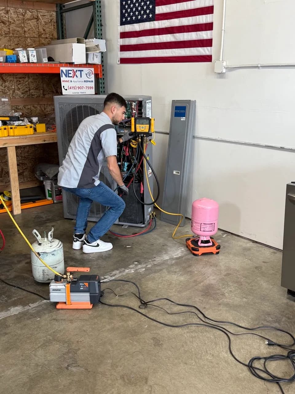 Technician charging an indoor unit with gauges and a recovery cylinder