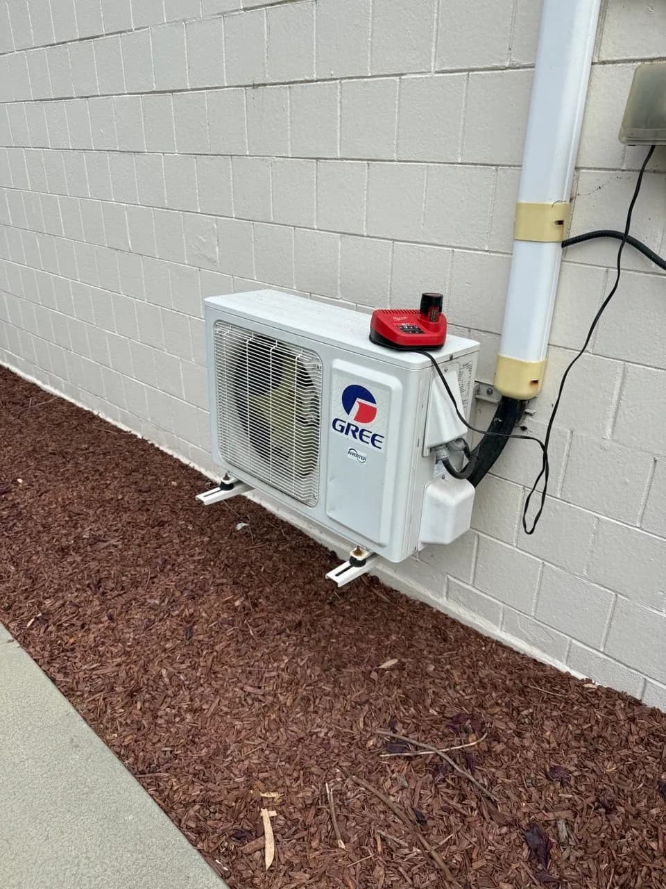 Ductless mini-split outdoor unit set on gravel beside a block wall