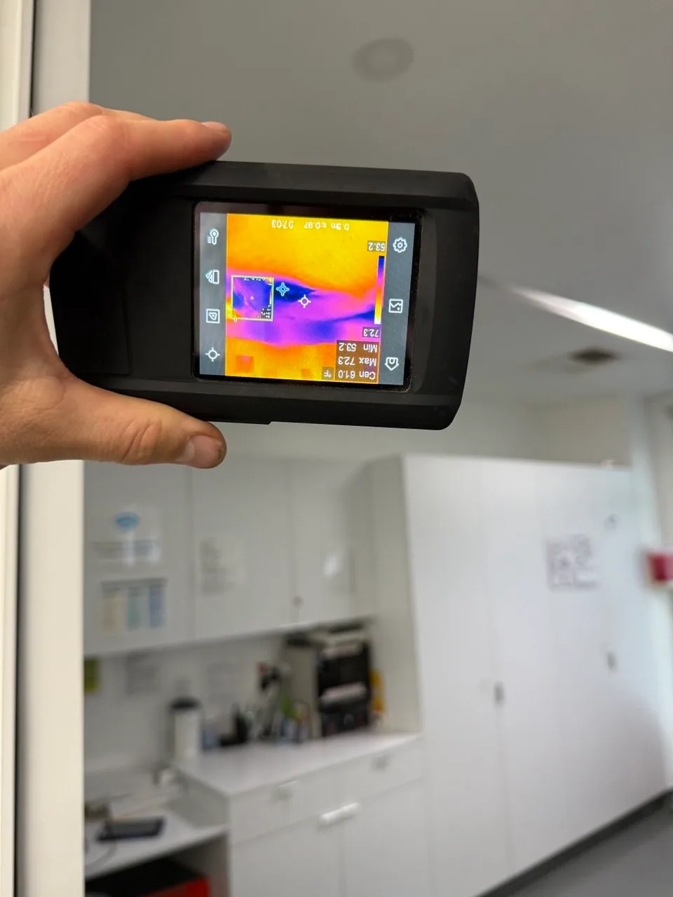 Technician scanning an interior wall with a thermal camera